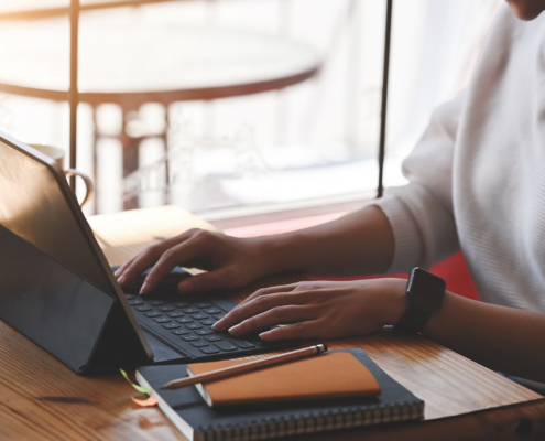 Side view of a woman typing on tablet keyboard